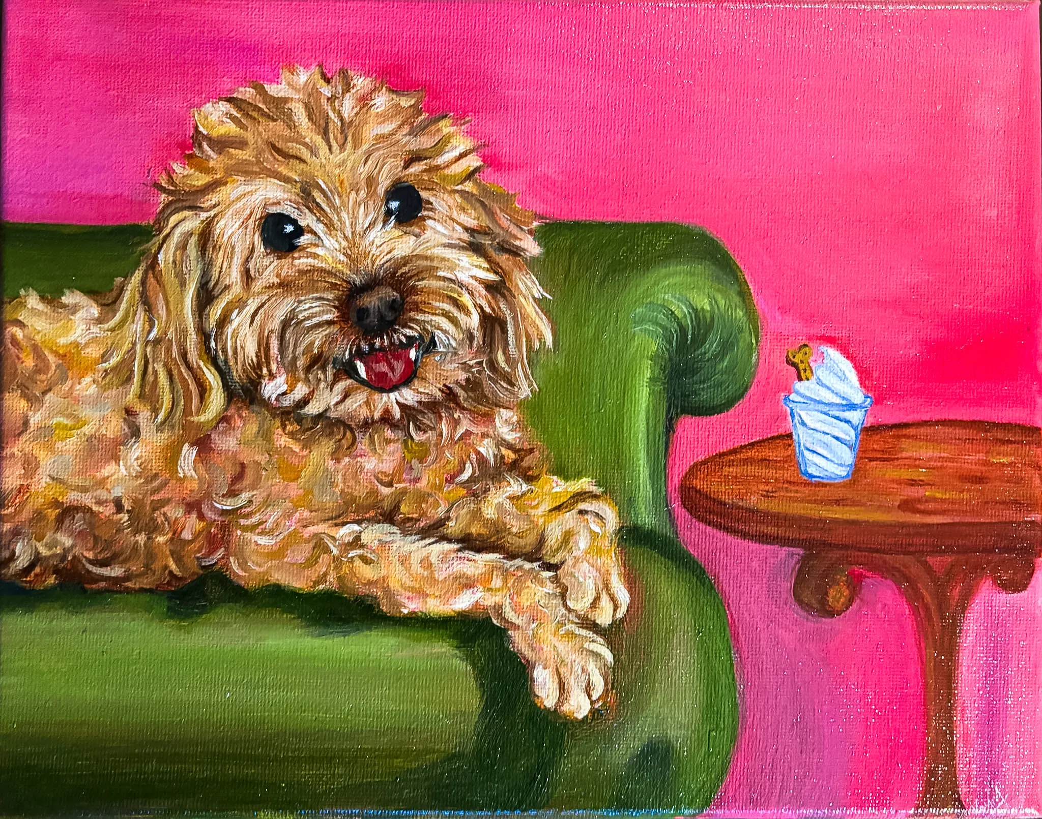 Oil painting of a scruffy golden doodle-type dog with dark eyes and his tongue out, draped over the arm of a green sofa, with a pup cup topped by a dog biscuit on a round wooden side table.